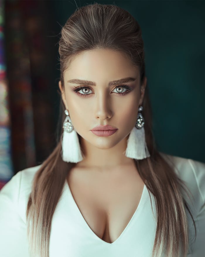 Portrait of a beautiful woman with striking eyes and elegant earrings, captured indoors.